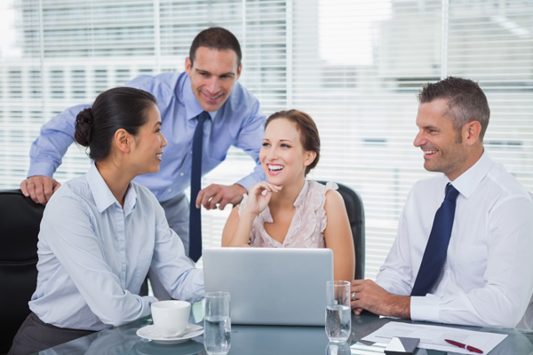 Cheerful colleagues around laptop working together in bright off