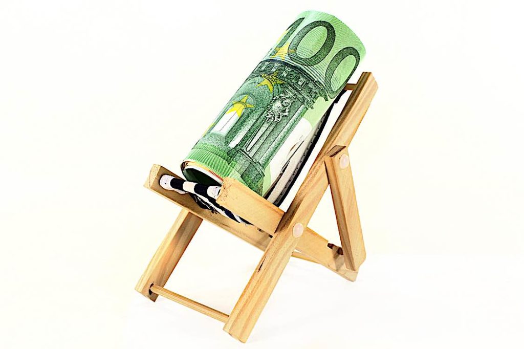 Holiday Pay roll of dollars in a reclining chair Pivotal HR Solutions Blog