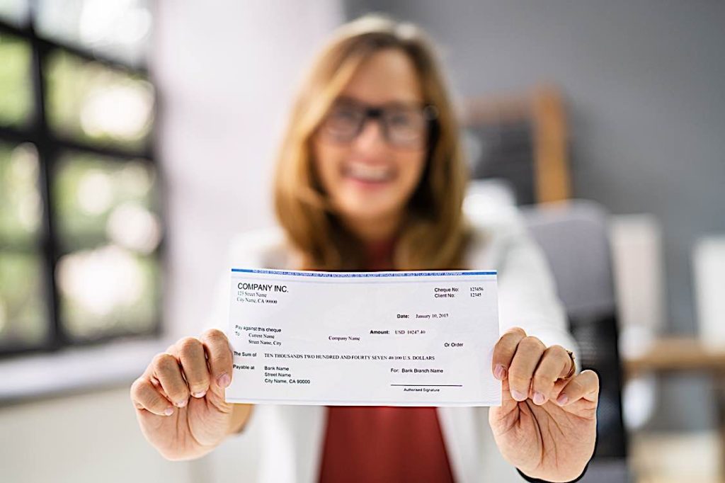 Happy Employee with paycheque dreamstime l 230007237 Pivotal HR Solutions Blog