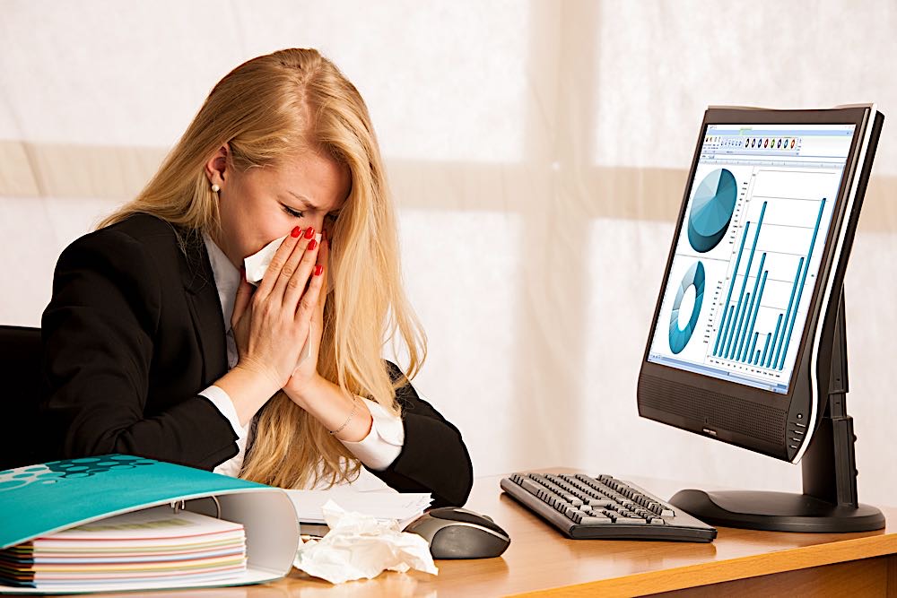 woman with flu in office dreamstime xl 109622154 Pivotal HR Solutions Blog