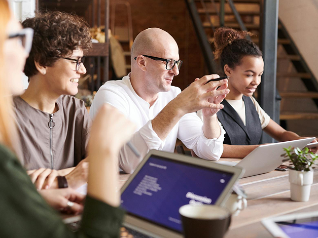 Coworkers at table looking at laptop