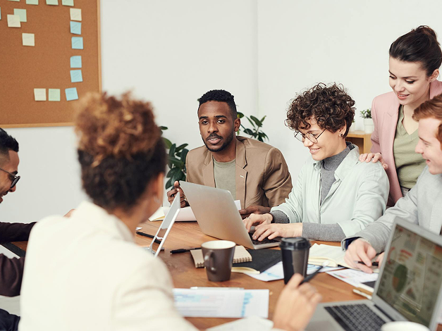 Coworkers in a meeting at desk with laptops