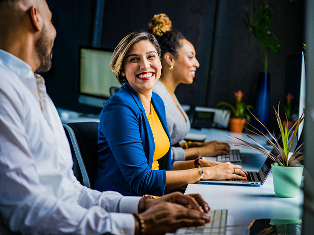 Coworkers smiling with working on laptops