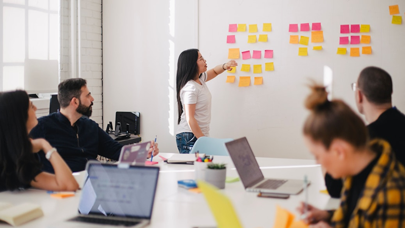 Woman placing sticky notes on white board
