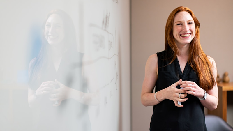Woman smiling beside whiteboard